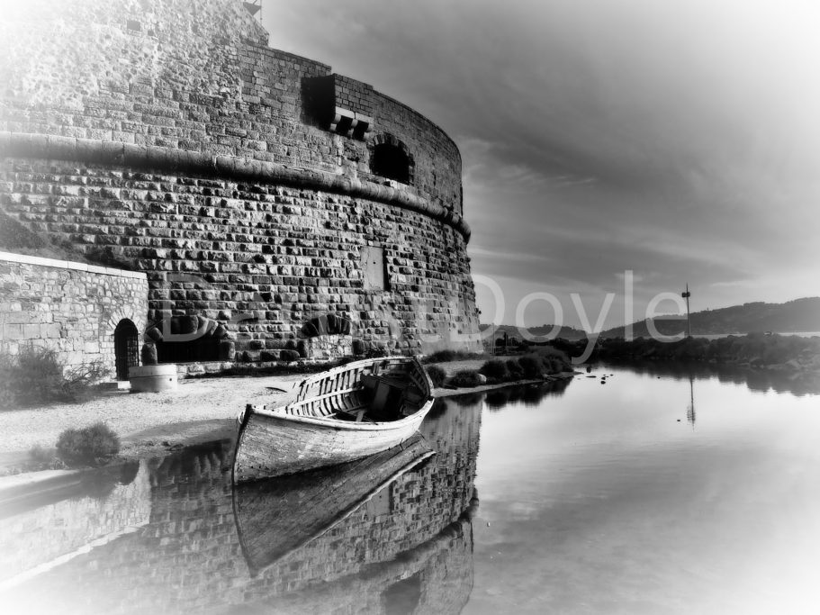 Château ancien en pierre reflété dans l'eau calme d'un port.