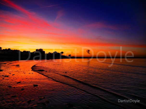 Coucher de soleil vibrant sur la mer, avec des reflets colorés et un horizon sombre.