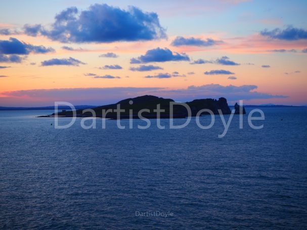 Île au coucher de soleil, avec des nuages et des reflets sur l'eau calme.