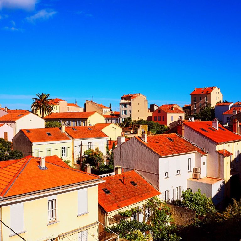 Vue panoramique d'un quartier résidentiel avec maisons aux toits rouges sous un ciel bleu.