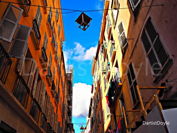 Ruelle étroite avec des bâtiments colorés et un ciel bleu parsemé de nuages.